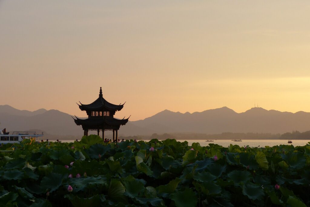 A sunset with a pagoda off to the side of it.