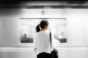 A woman standing in front of train. Figuring out which way to go. Representing life's decisions and how that can increase anxiety and depression.