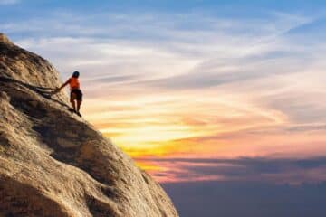 Climber conquers rock face at sunset, embracing the thrill and challenge. Signifies the Zhi or willpower